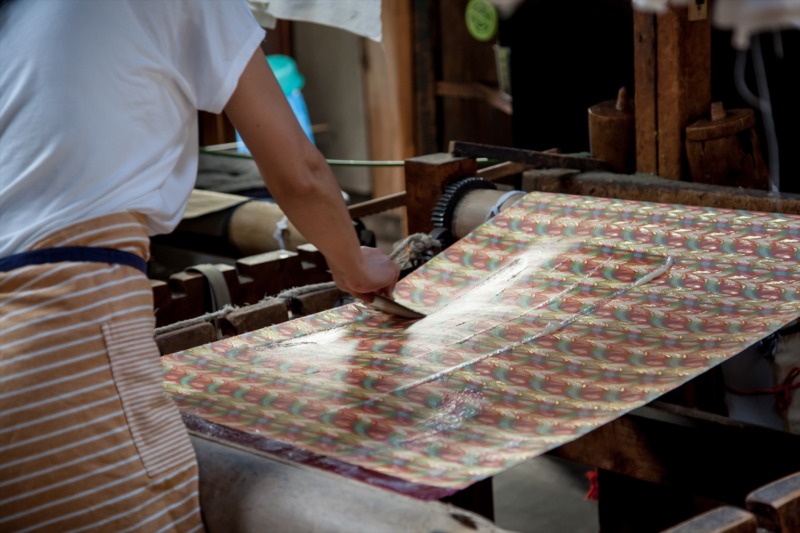 西陣織 金襴の最終工程である糊を張る加工。これは、反物の整理加工、風合いの維持などに必要な加工で「張り屋」という専門の職人がいます。