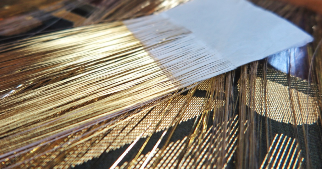 緑地の西陣織本金引箔金襴麻の葉紋様地の上に本金引箔糸を置いた写真