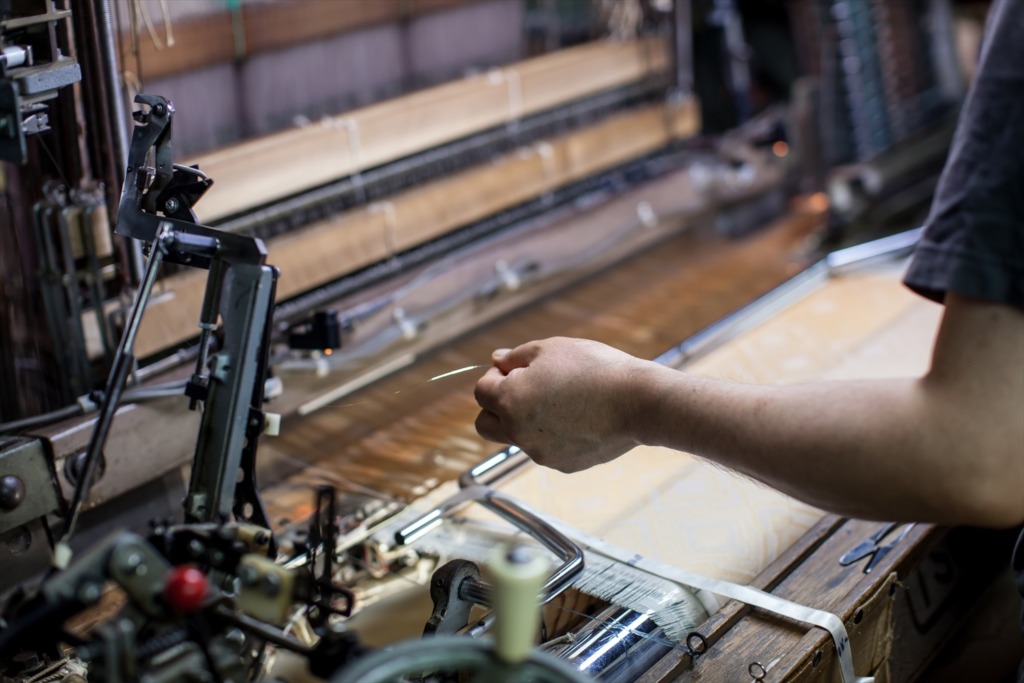 西陣織 金襴を力織機で織る職人の手のアップ画像