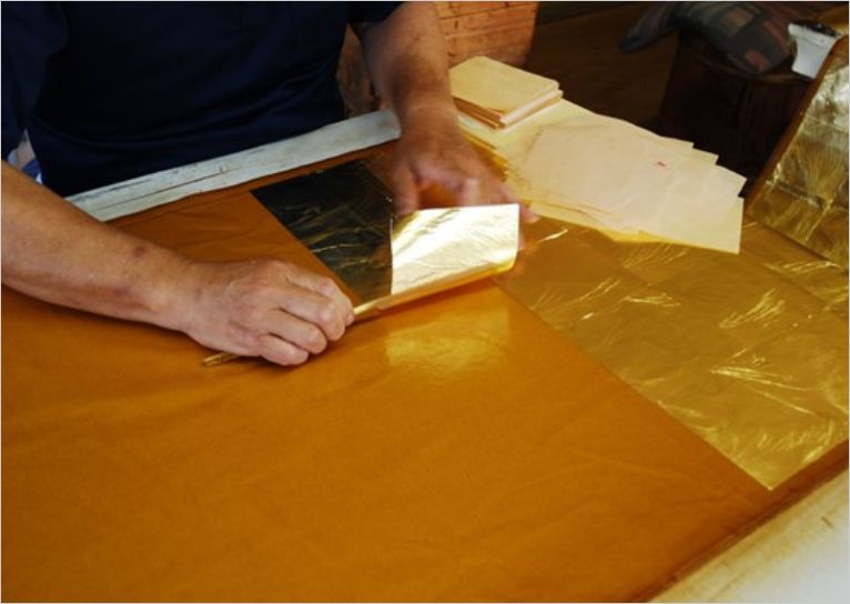 本金引箔を作る箔職人。和紙に漆を塗り本金箔を貼っている所のアップ画像